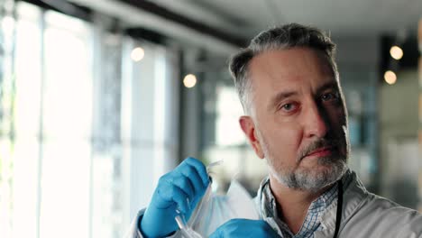 primer plano del médico quitándose la máscara médica y las gafas y mirando la cámara en la clínica