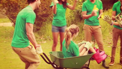 man pushing his friend in wheelbarrow with friends behind
