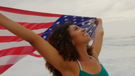 Vorderansicht-Einer-Afroamerikanischen-Frau-Mit-Wehender-Amerikanischer-Flagge,-Die-Am-Strand-4k-Tanzt