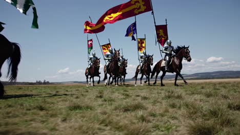 Low-angle video shot of knights on horseback charging across a field, showcasing medieval armor