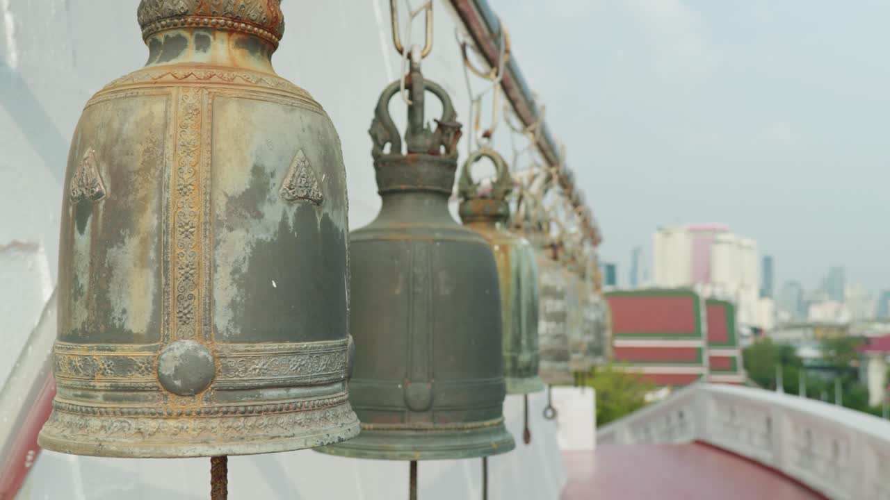 Filmato cinematografico 4K al rallentatore di grandi campane buddhiste del tempio a Wat Saket, il Monte d'Oro, Bangkok, durante una giornata di sole.