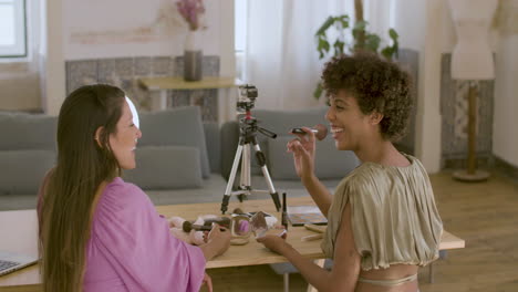 back view of two female beauty bloggers recording video together