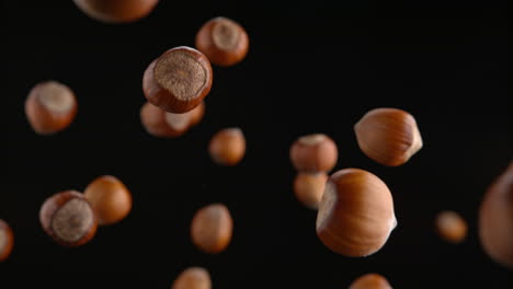 hazelnuts in shells flying on the black background in macro and slow motion