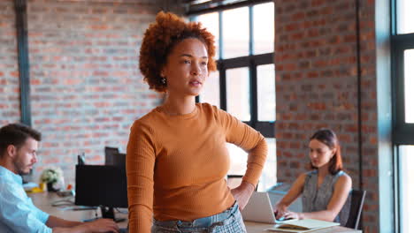 portrait of serious businesswoman in office with colleagues working in background