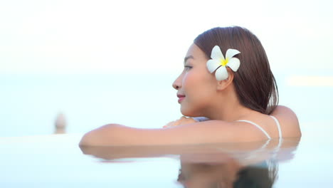 beautiful asian woman daydreaming at the side of the swimming pool