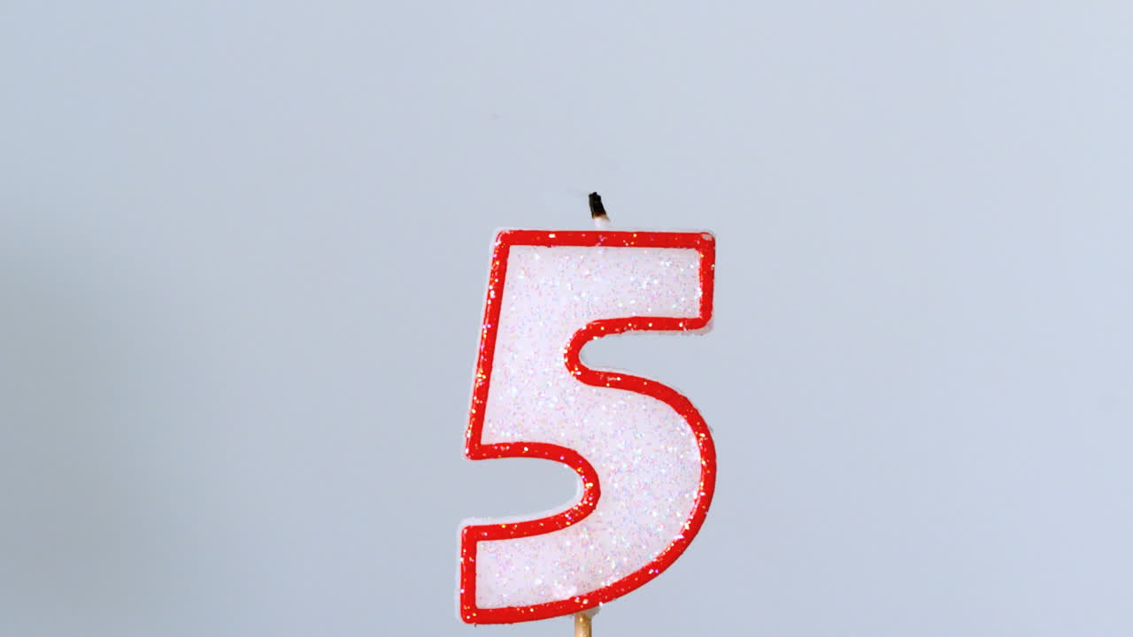 cinco velas de cumpleaños parpadeando y apagándose sobre un fondo azul