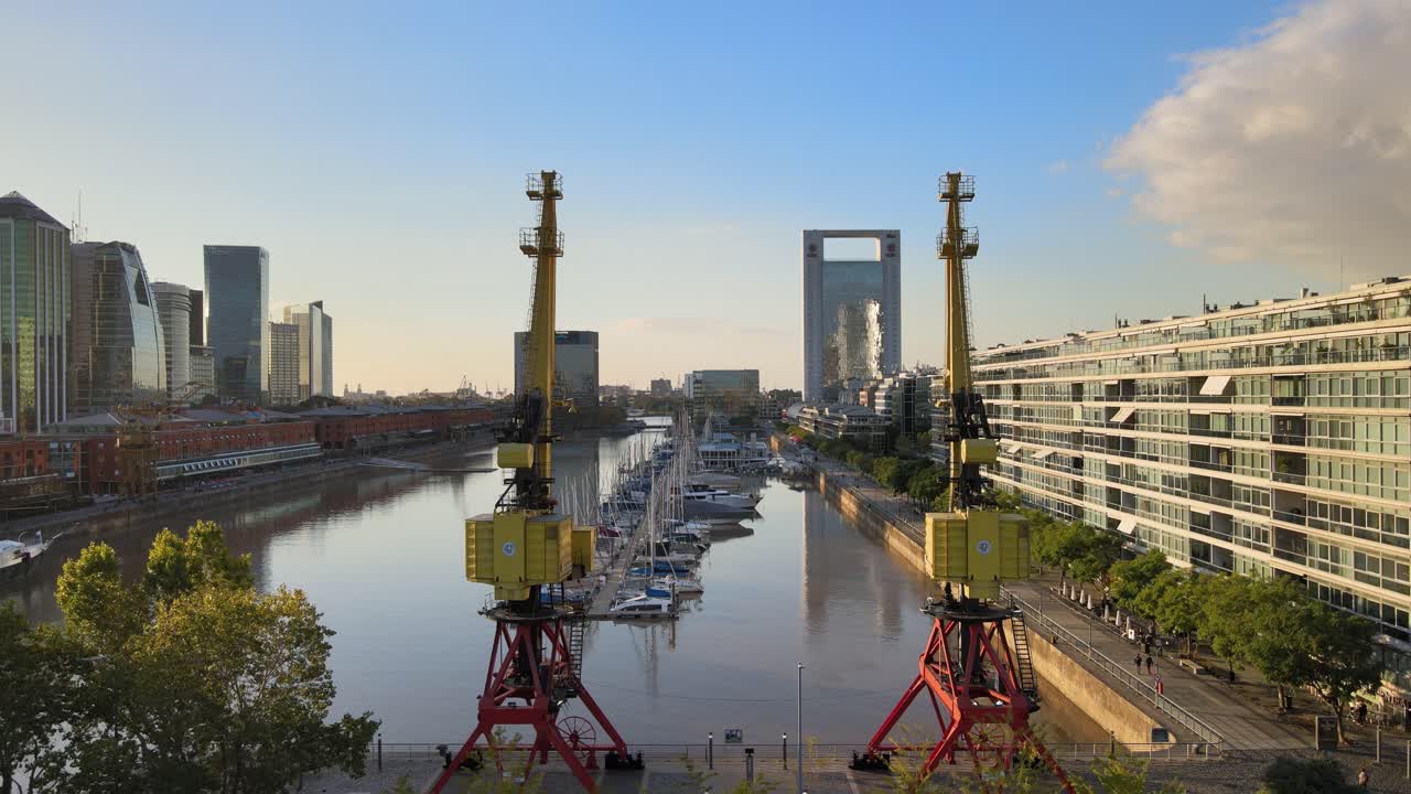 골든 아워에 푸에르토 마데로 해안가에 있는 두 개의 오래된 항구 크레인을 드러내는 공중 돌리