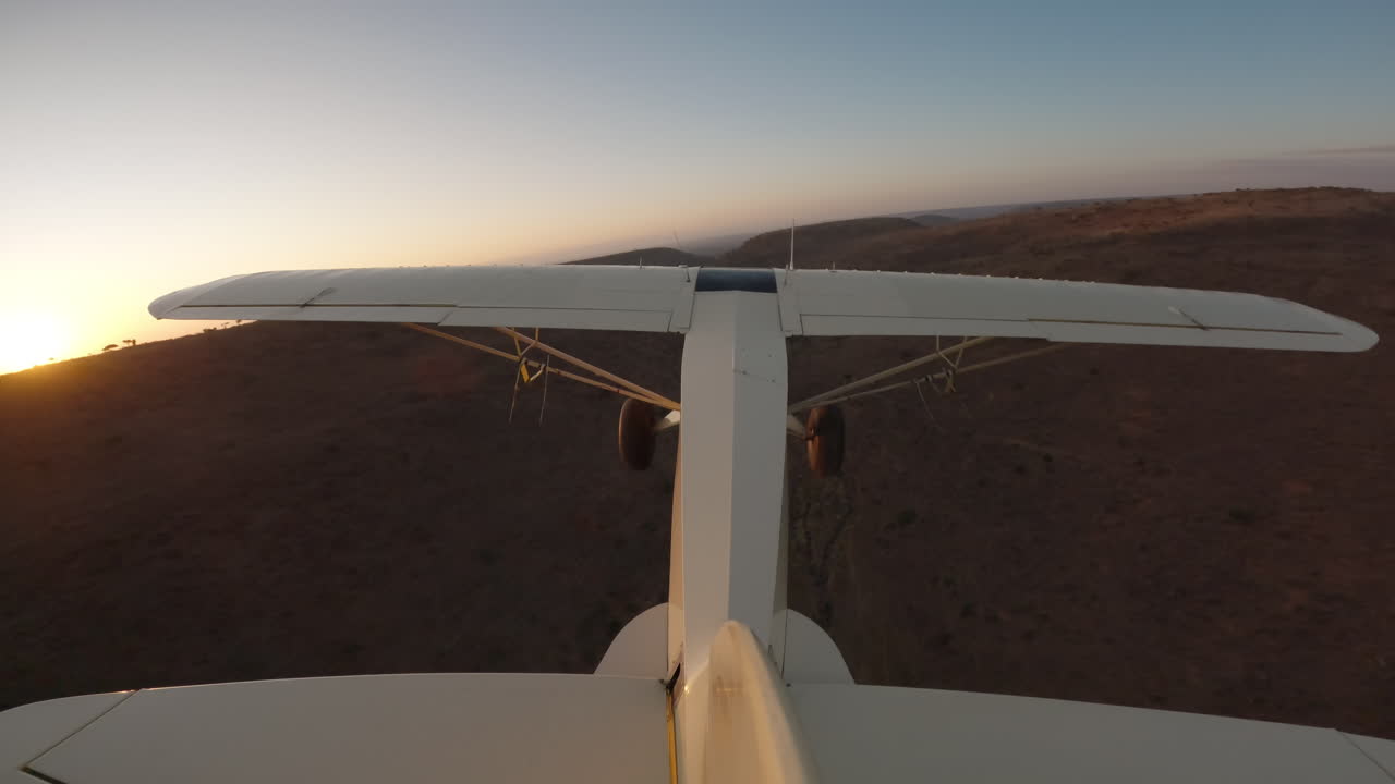 Aereo da boscaglia in volo sopra le scarpate al tramonto
