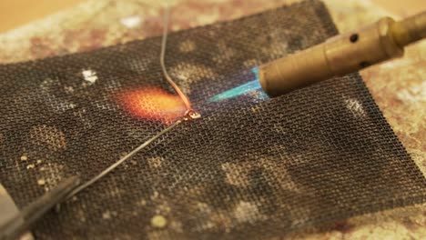 soldering metal wires with butane gas flame burner - close up shot