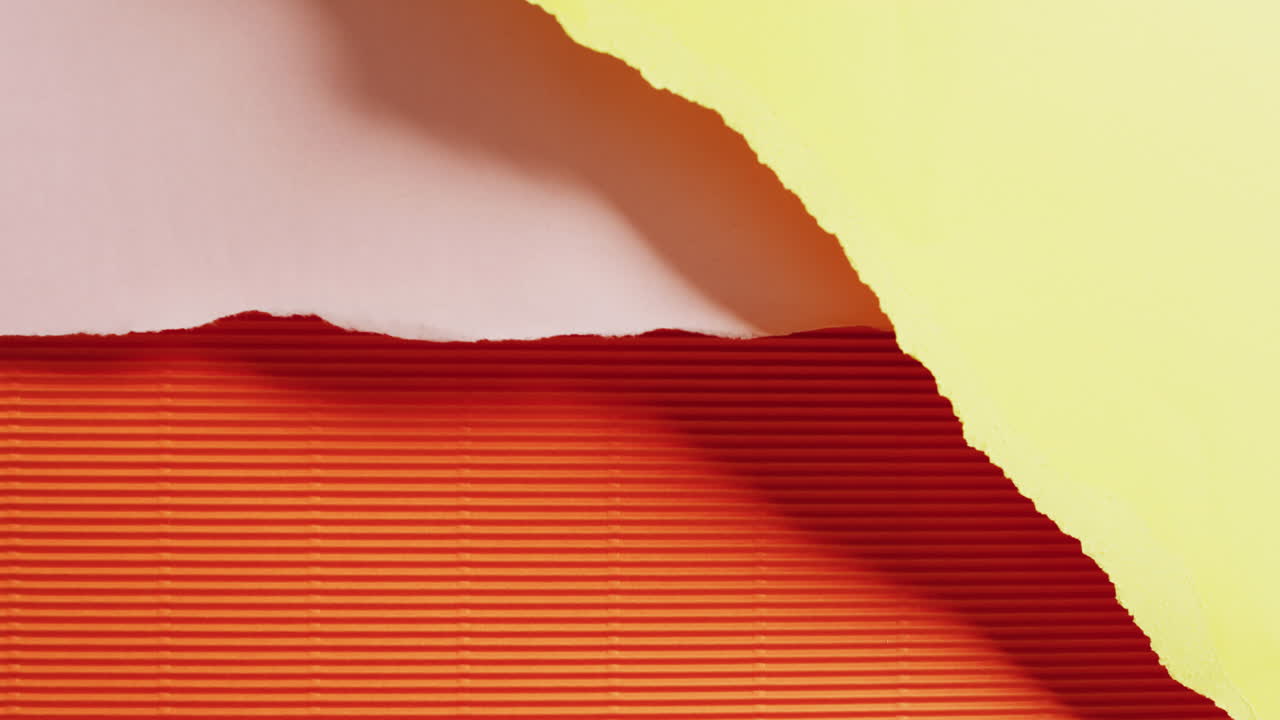 Video of close up of torn pieces of yellow, pink and orange striped paper background