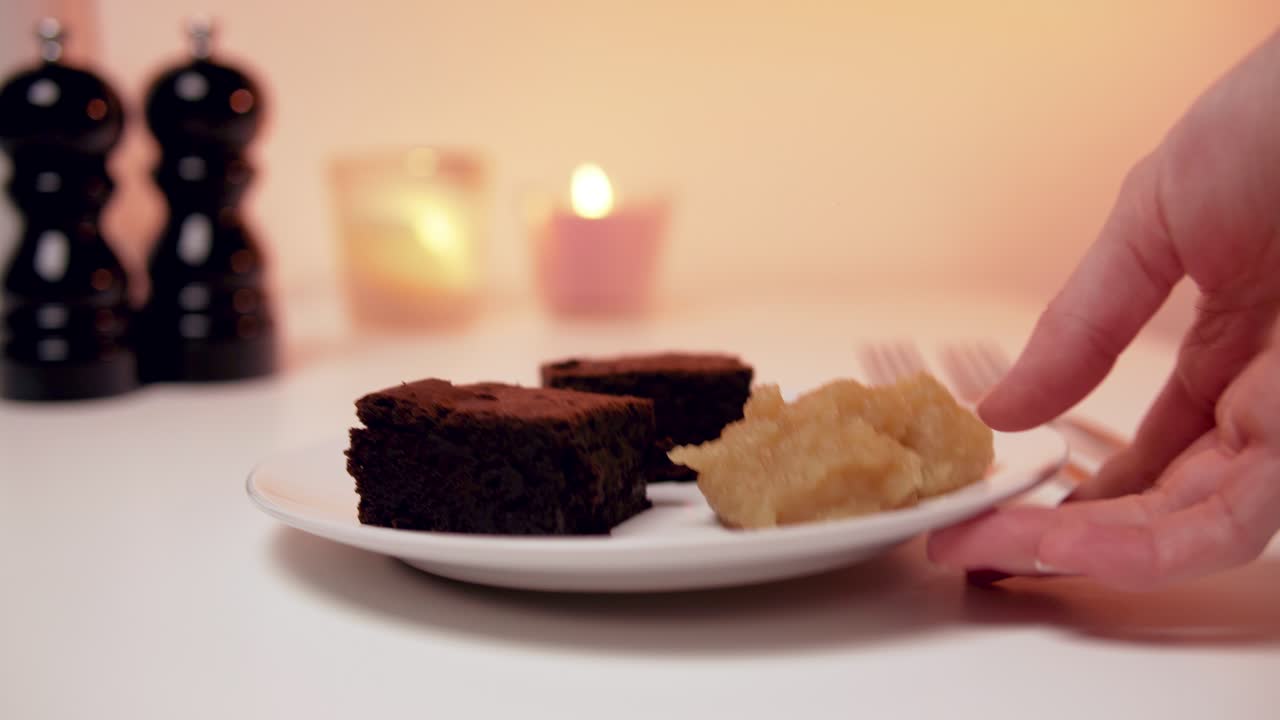 맛있어 보이는 낭만적인 사막:백고운드에 촛불이 있는 하얀 접시에 사과 소스를 곁들인 브라우니