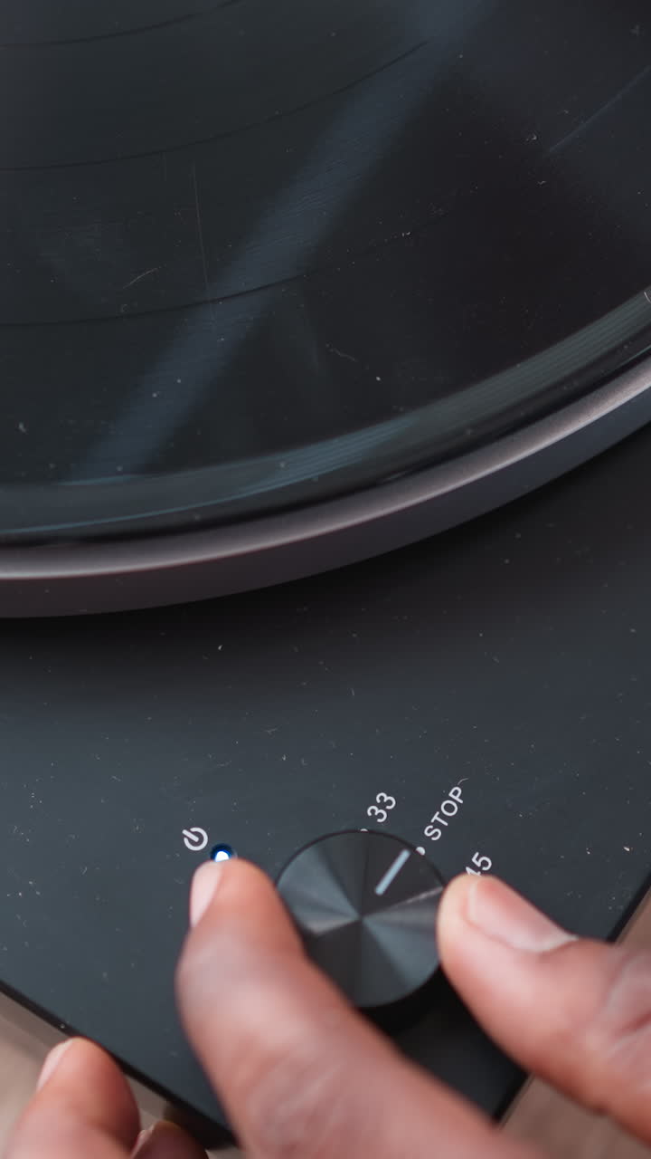 Hand of man turning on switch on turntable. African American music enthusiast spends weekend indulging in favorite tunes through vintage turntable. Evening leisure