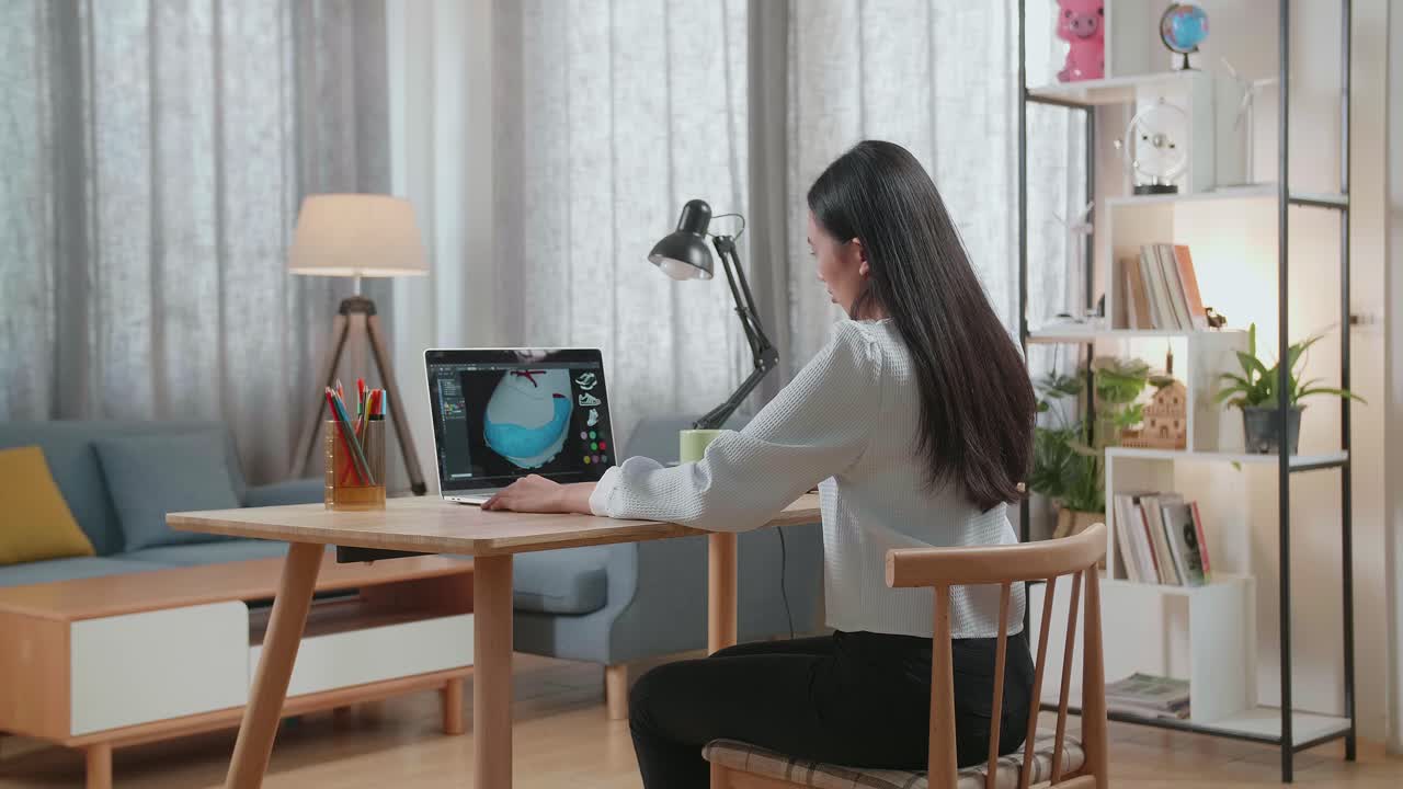 가정 사무실에서 노트북으로 신발 디자인을 하는 여성