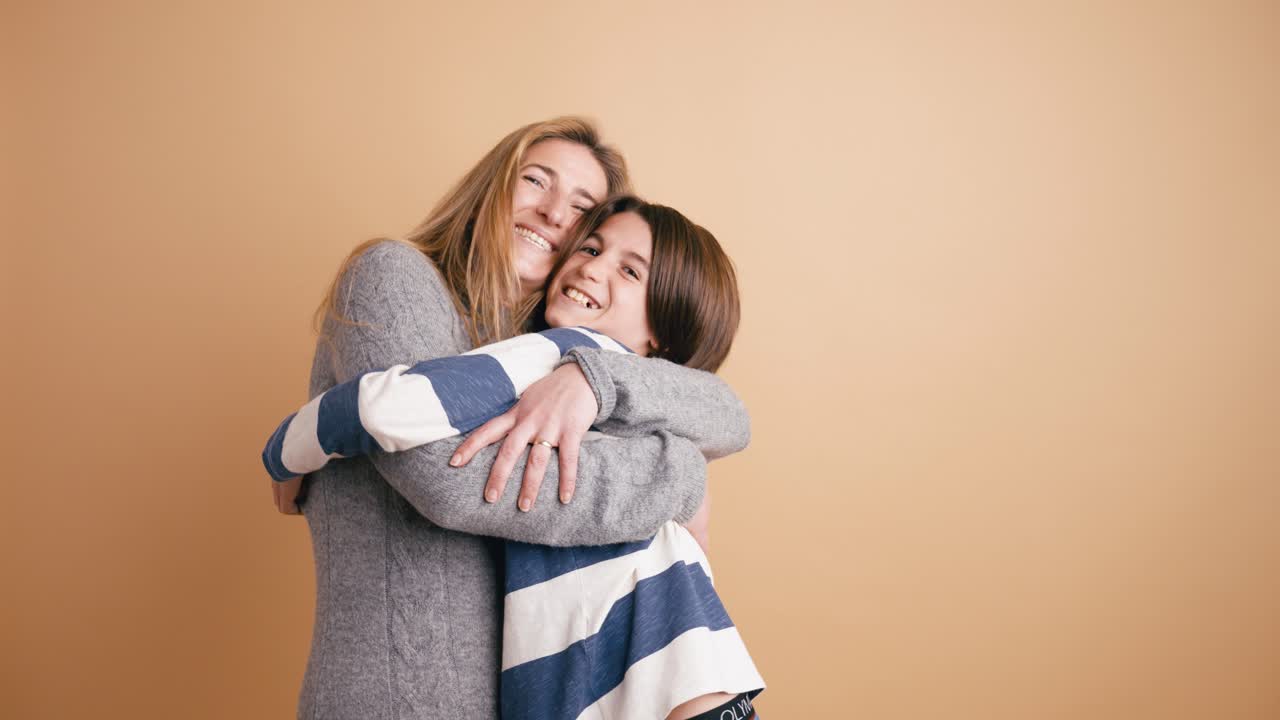 Madre e figlio felici si abbracciano e sorridono in studio