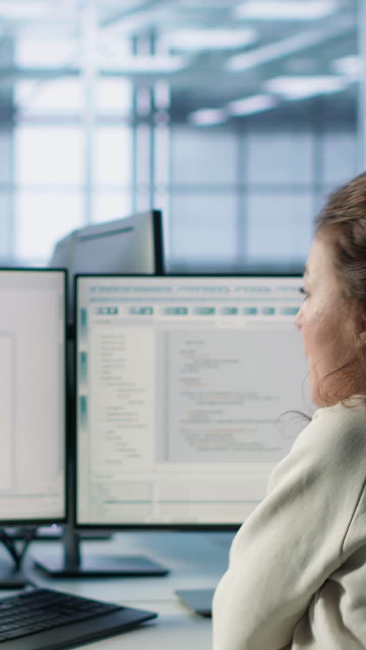 Female Programmer Typing Code on Dual Monitors in Modern Office