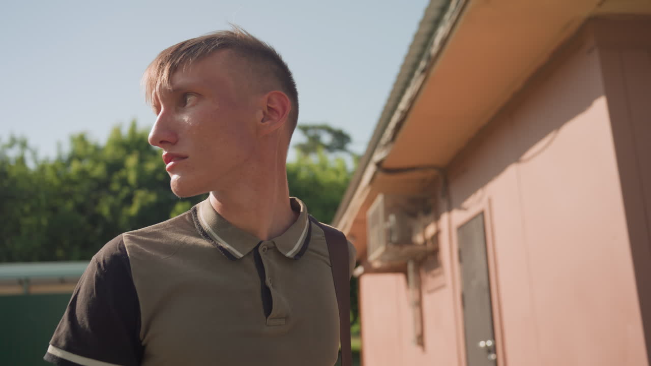 Male Walking Cautiously, Individual Advances Cautiously Past Structures With Tense Awareness, Person Moves Deliberately Past Trees And Sheds Displaying Visible Signs Of Nervousness And Attentiveness