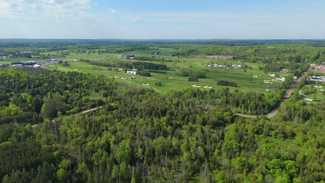 Wide drone view of golf course and forest in sunny Ontario, Canada