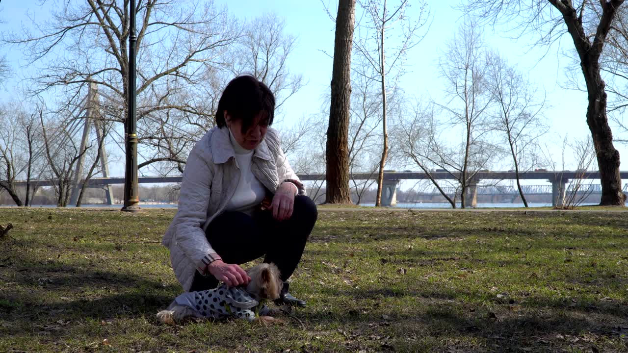 할머니는 앉아서 작은 개를 만져요.