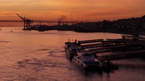 orange sunset haze on ferry dock ports on tagus river in lisbon portugal, aerial orbit