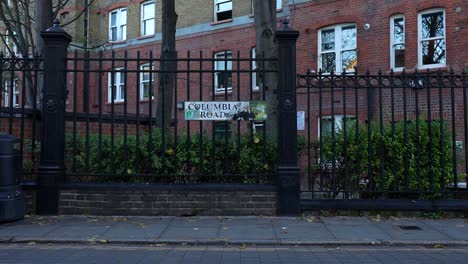 backpacker walks along columbia road towards the flower and plant market, london