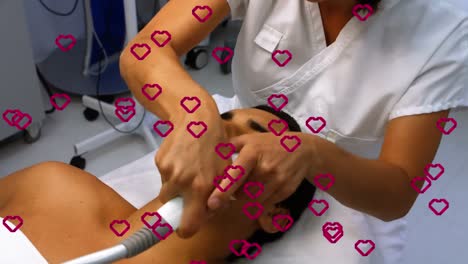 animación de corazones flotando sobre un paciente masculino biracial y una doctora durante el tratamiento con láser