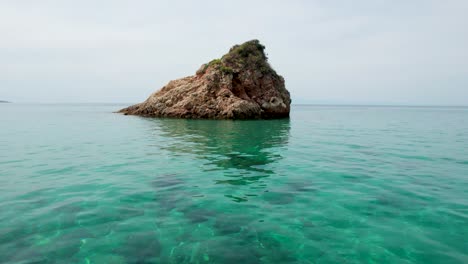 Camera-Moving-Close-To-The-Sea-Waves-With-Turquoise-Water-And-A-Small-Island-In-The-Foreground,-Thassos-Island,-Greece,-Europe