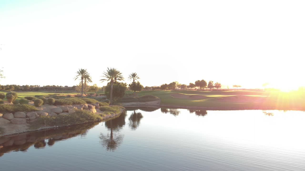 Drone footage from a golf course near a residential neighborhood in Arizona. Low aerial shot of a water hazard