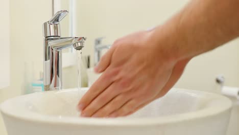 Mid-section-of-man-washing-hands-in-basin-4k