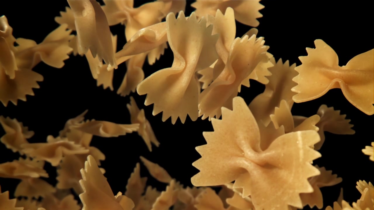 Pasta farfalle cruda che cade e fluttua su uno sfondo nero