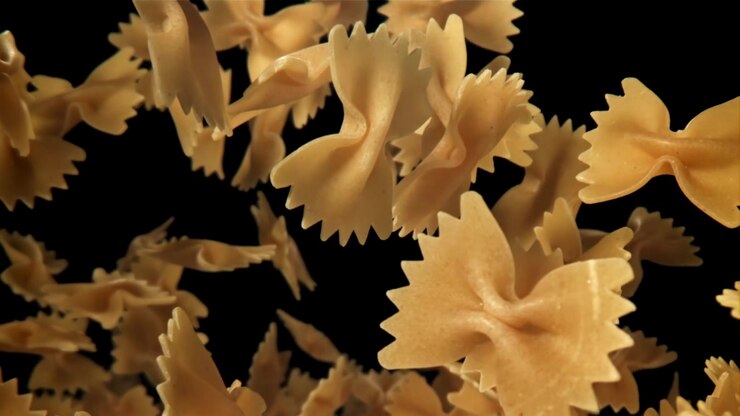 Pasta farfalle cruda che cade e fluttua su uno sfondo nero