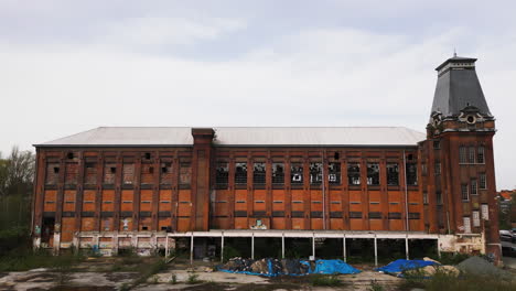 Red-color-abandoned-building-with-tower,-aerial-ascend-view