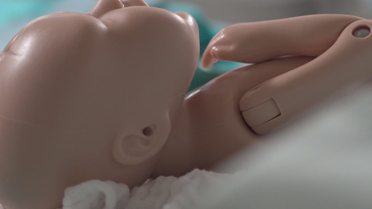 Studente di infermieristica impara a prendersi cura di una bambola neonato