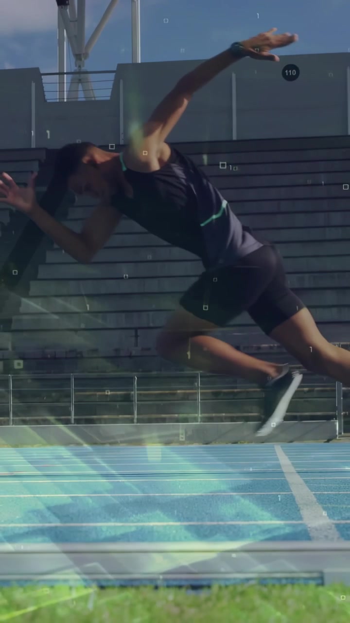 Vertical video: Male sprinter pushing off start line, driving down blue track past stands for sport