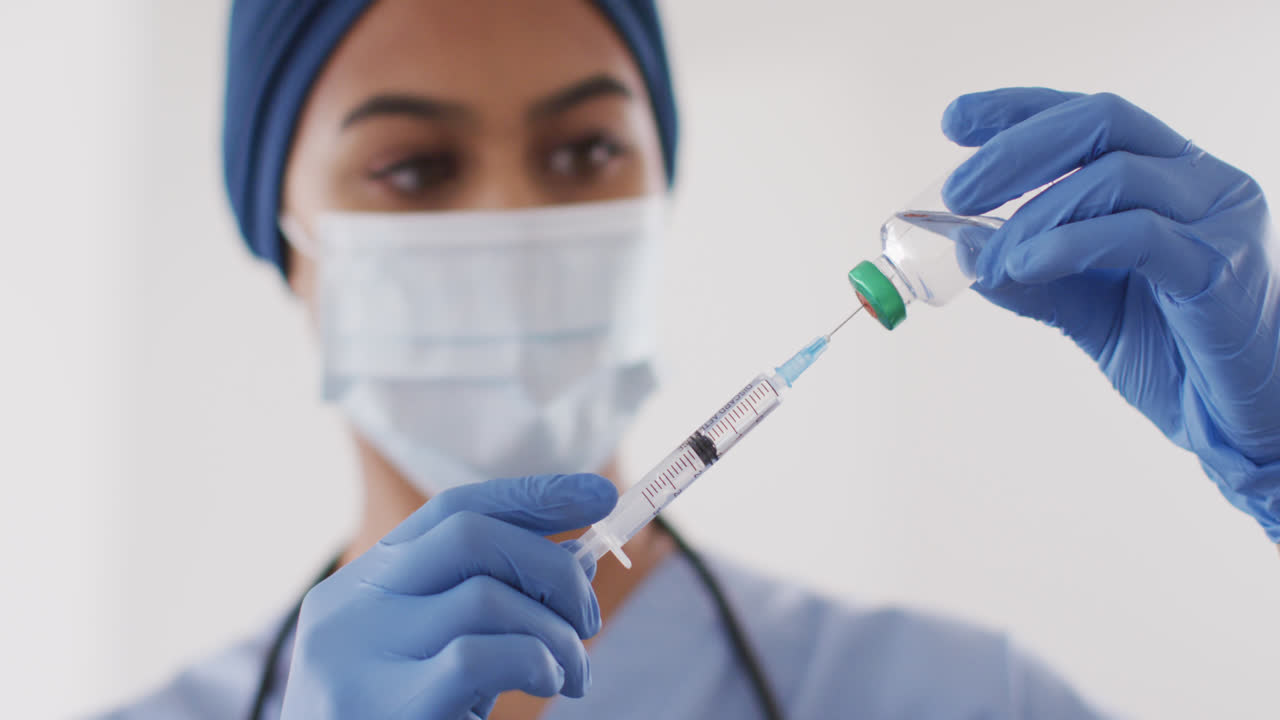Video of biracial female doctor in face mask with vaccine