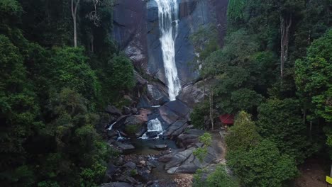 aerial view by drone of tropical waterfall in langkawi, malaysia. young couple enjoying themselves and woman waving to the camera