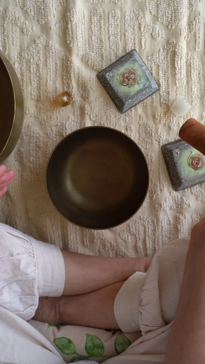 Vertical Top View Of A Person Holding A Mallet Rotating And Striking A Tibetan Singing Bowl