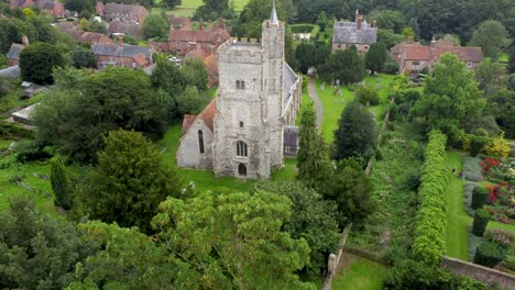 aerial reveal of old church behind tree in parish village in kent