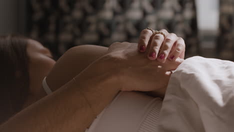 close-up of loving couple holding hands in bed