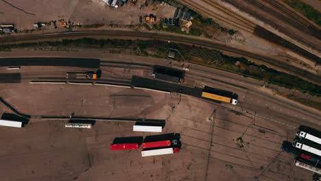 aerial view above a trucks passing a entrance point at a shipping terminal - top down, drone shot