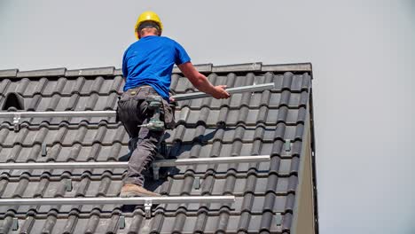 técnico caucásico que perfora la construcción de paneles solares en la azotea, a cámara lenta