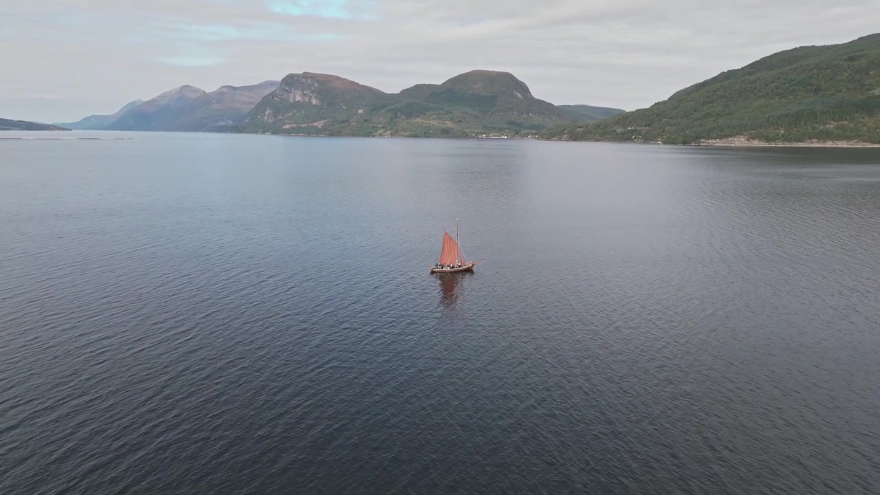 Vecchia barca a vela con vela arancione nella zona dei fiordi della Norvegia