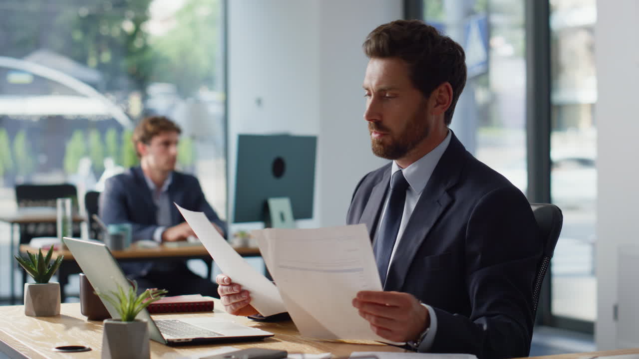 Focused financier working documents looking laptop office closeup. Man worried