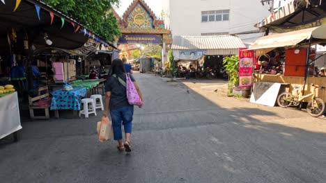 person walking past market stalls towards temple