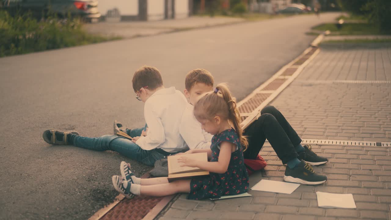 niños pequeños juegan con libros y sábanas en el pavimento