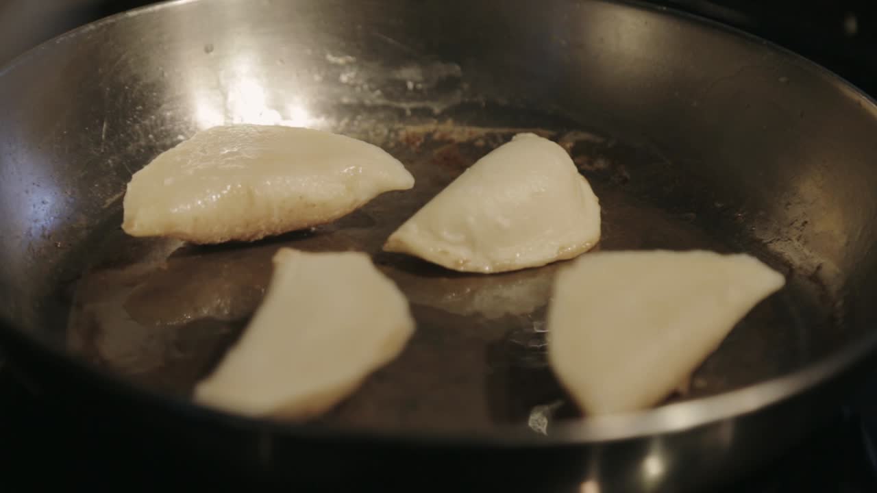 Canada - Frying Four Dumplings In A Stainless Pan With Little Amount Of Cooking Oil - Closeup Shot