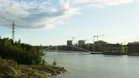 Antenne,-Niedrig,-Drohne-Schoss-An-Einem-Sonnigen-Abend-In-Helsinki,-Uusimaa,-Finnland,-Auf-Ein-Boot-Zu,-Das-Unter-Der-Isoisansilta-Brücke-Zwischen-Der-Insel-Mustikkamaa-Und-Dem-Stadtteil-Kalasatama-Fährt