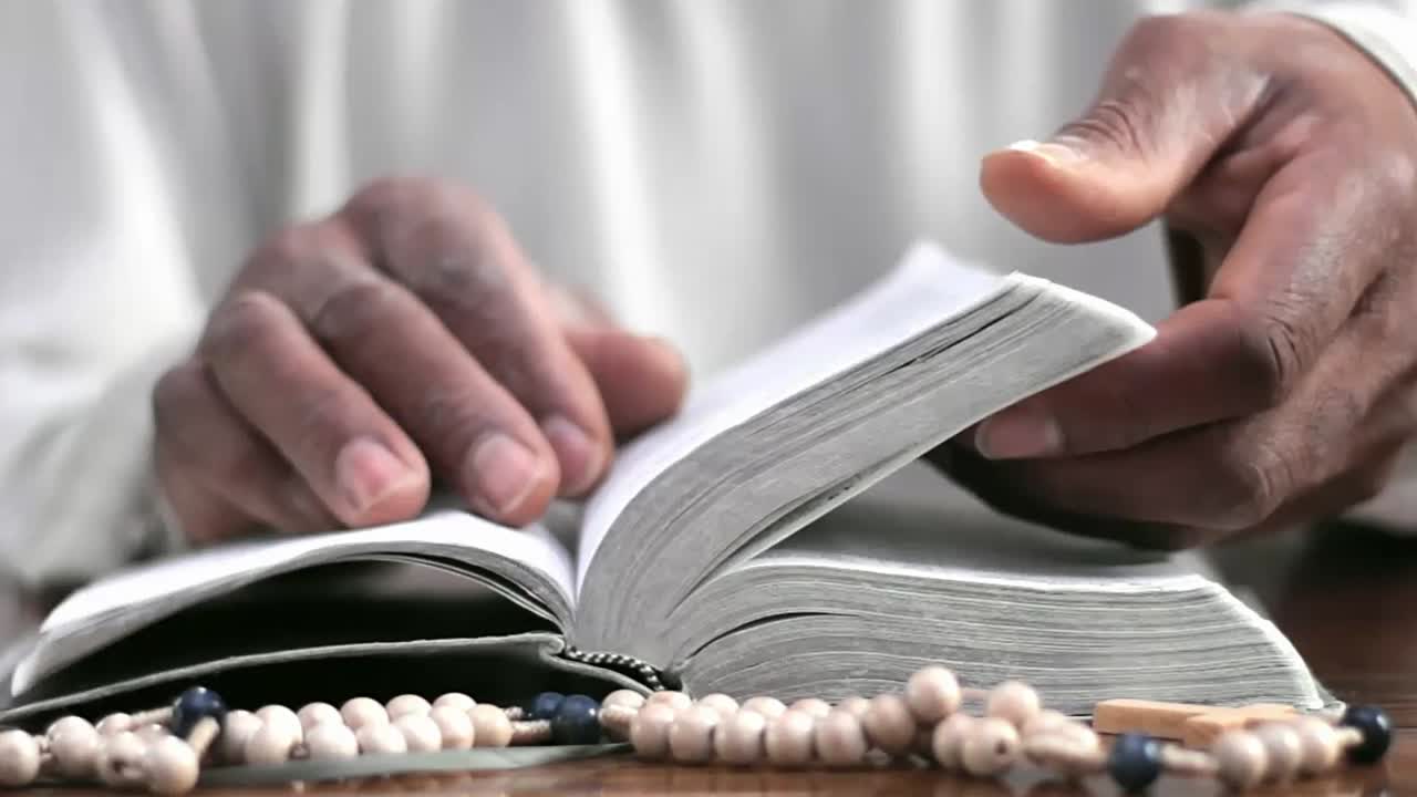Mani che pregano Dio su una Bibbia con persone - Filmato video in stock