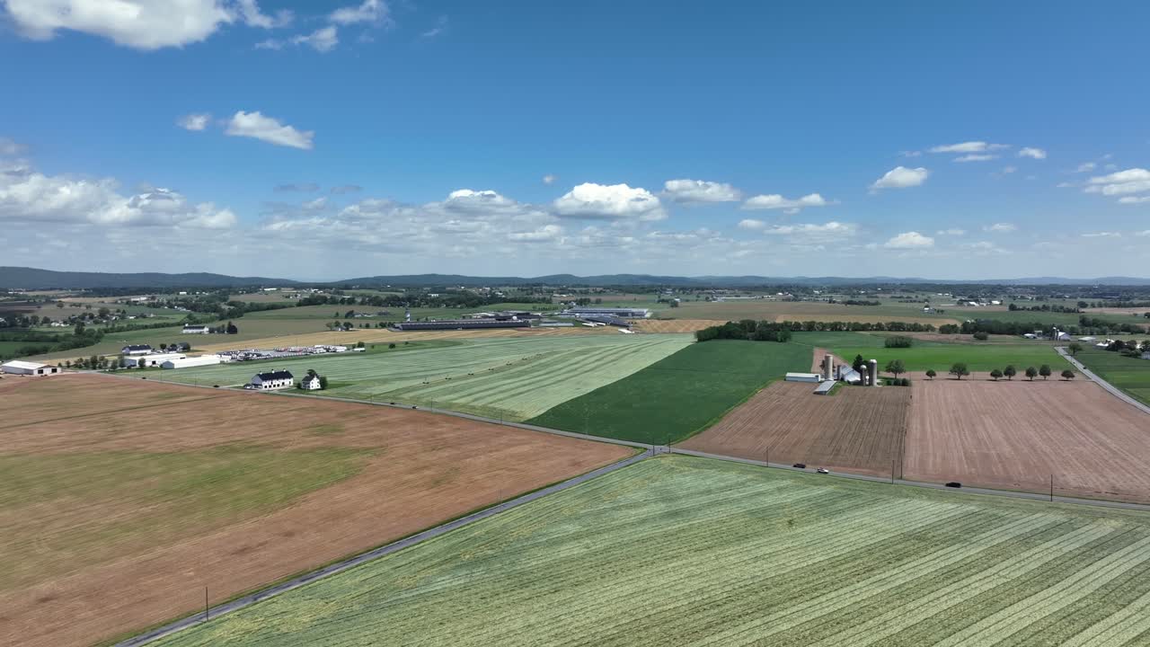 American agricultural farm fields and traffic on intersection road of American town. Rising drone wide shot. Sunny day with blue sky in spring season. Panorama view.
