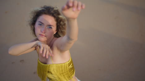 trendy girl dancing passionately at evening sunlight on nature sand close up.