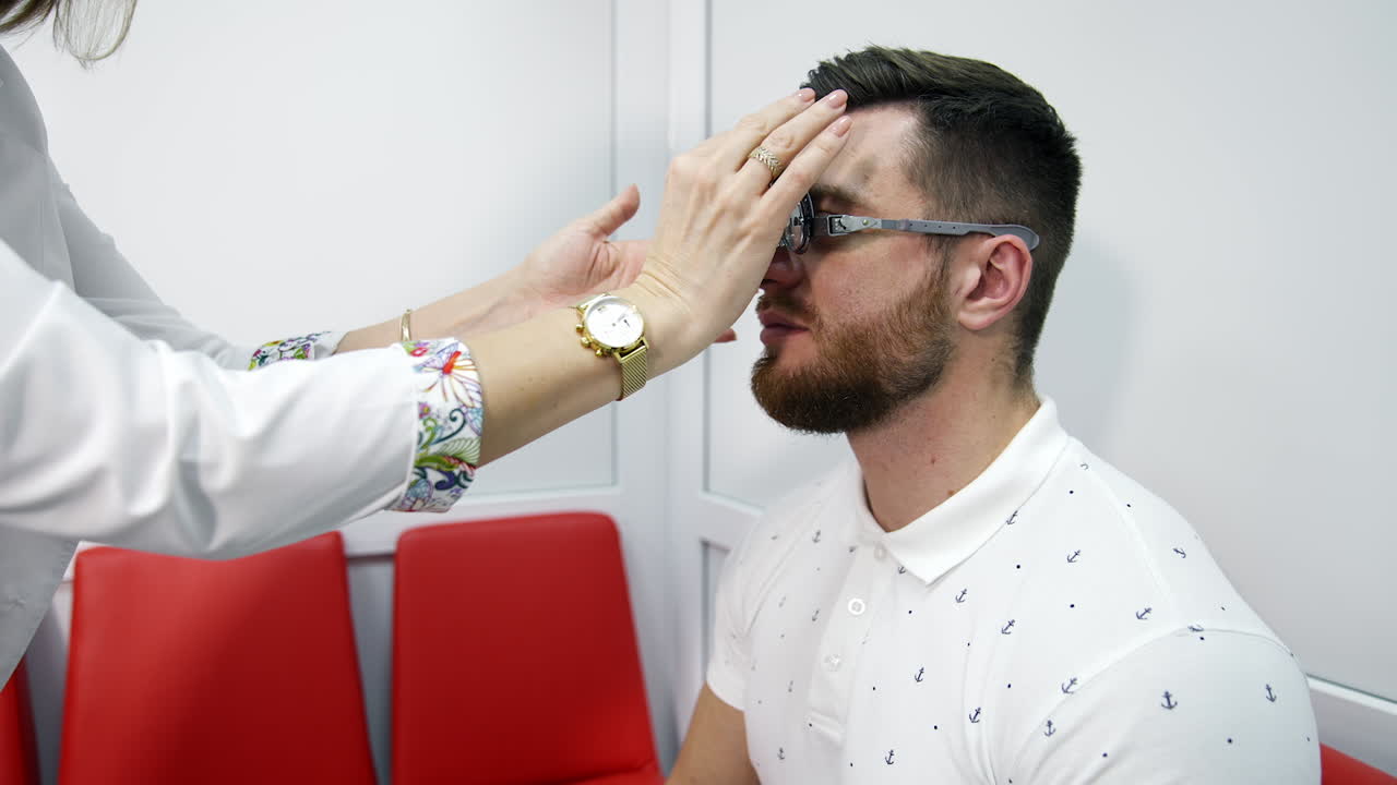 Checking eyesight. Doctor customises lenses on trial frame to a patient. Profile view of a young man in testing glasses in optical clinic.